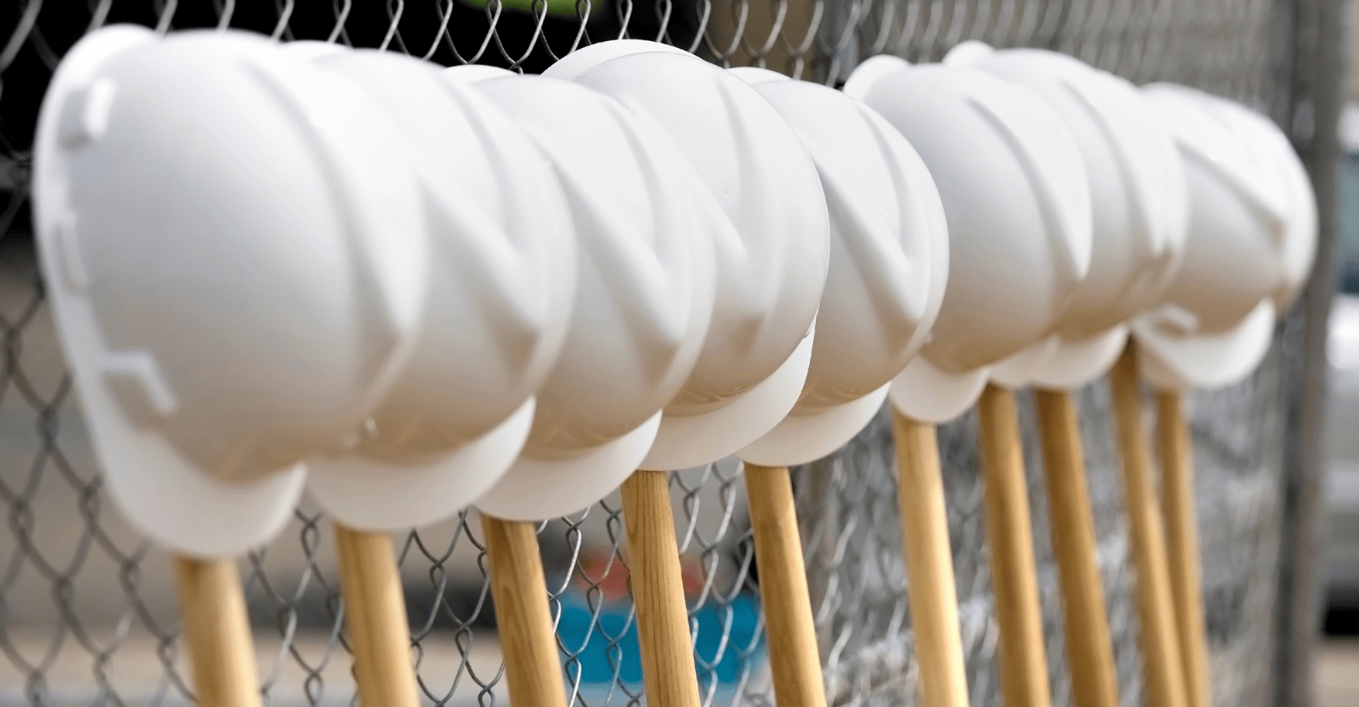 Hard Hats on Shovels Against a Fence